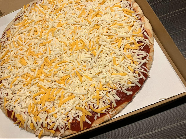 トマトソースの上に黄色と白のシュレッドチーズ